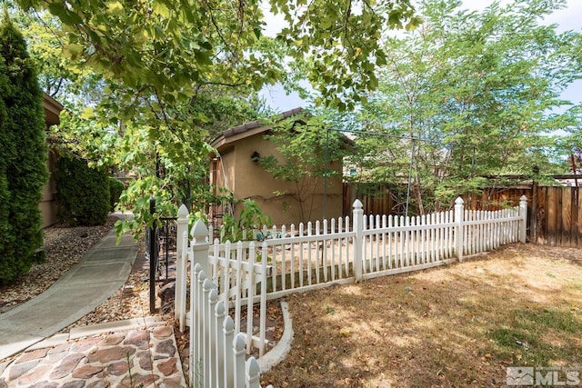 view of property exterior featuring a tiled roof, a fenced front yard, and stucco siding