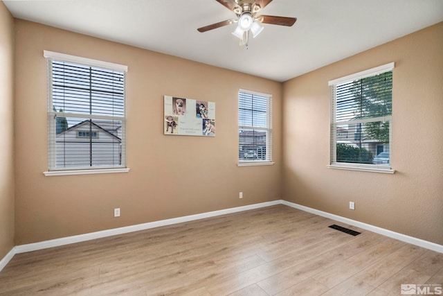 unfurnished room featuring a ceiling fan, baseboards, visible vents, and light wood finished floors