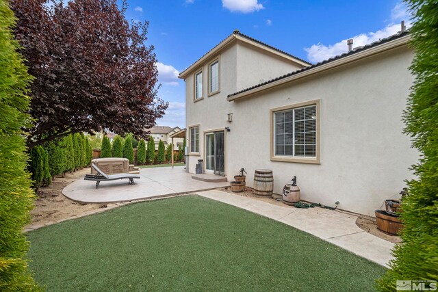 back of property featuring a lawn and a patio area