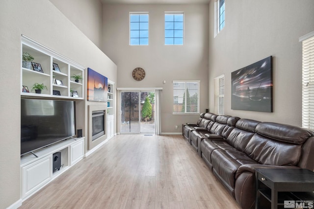 living room with light hardwood / wood-style floors, a high ceiling, and built in features