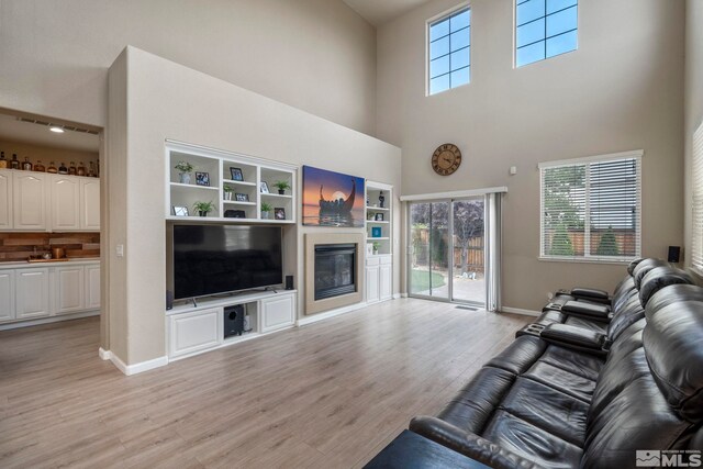 living room with a towering ceiling and light hardwood / wood-style flooring