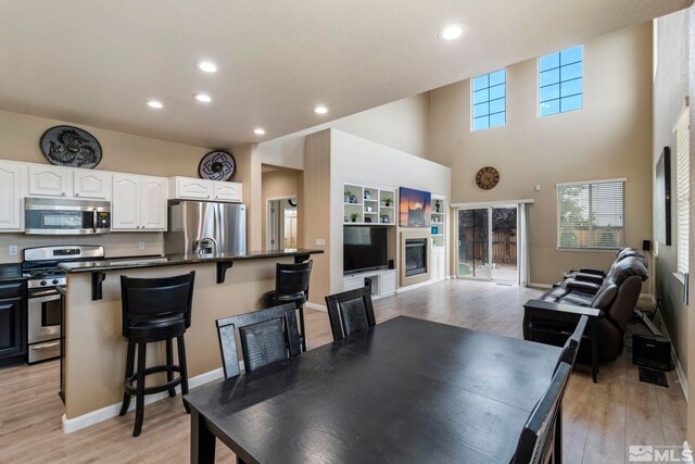 dining room with light hardwood / wood-style flooring and a high ceiling