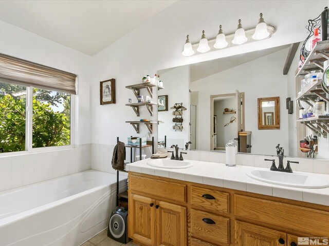 bathroom with lofted ceiling, a bath, and vanity