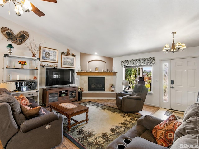 living room featuring vaulted ceiling, ceiling fan with notable chandelier, and light wood-type flooring