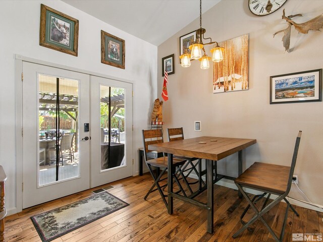 dining area featuring light wood-type flooring, french doors, an inviting chandelier, and lofted ceiling