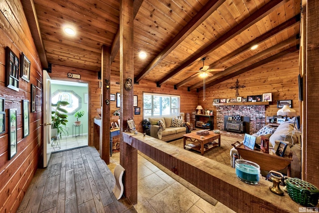 living room featuring wood walls, vaulted ceiling with beams, hardwood / wood-style floors, a fireplace, and wooden ceiling