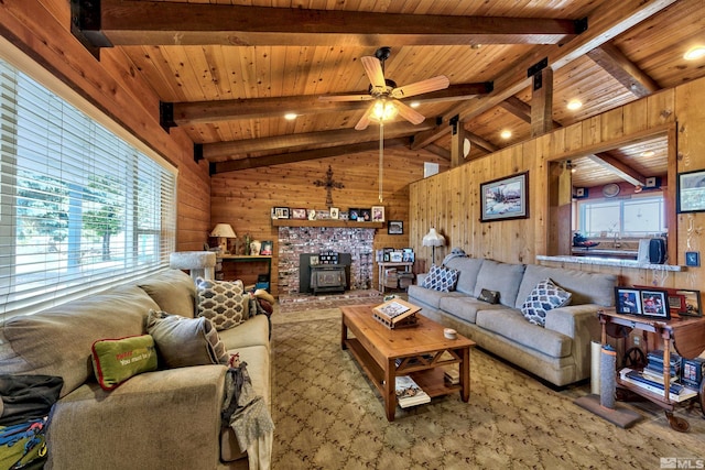 carpeted living room featuring lofted ceiling with beams, wooden walls, wood ceiling, ceiling fan, and a brick fireplace