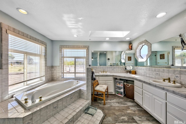 bathroom with backsplash, a skylight, vanity, and a healthy amount of sunlight