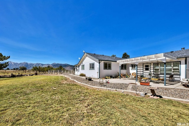 back of house with a pergola, a mountain view, a lawn, and a patio