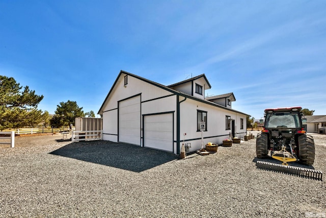 view of property exterior with an outbuilding, driveway, an attached garage, and fence