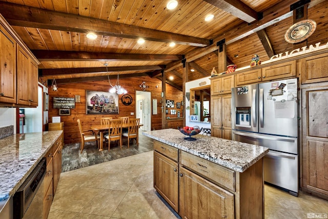 kitchen with wooden walls, appliances with stainless steel finishes, light stone counters, and a kitchen island