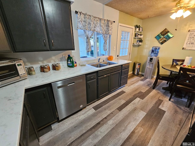 kitchen with ceiling fan, light wood-type flooring, dishwasher, sink, and a textured ceiling