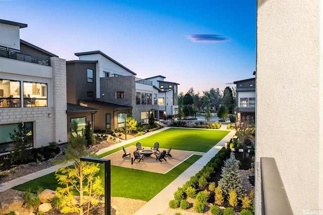 view of property's community featuring a patio area, a yard, and an outdoor fire pit