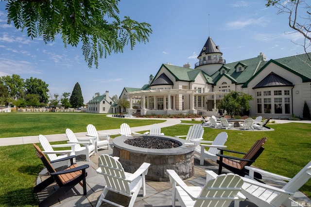 rear view of property with a patio area, a fire pit, and a lawn