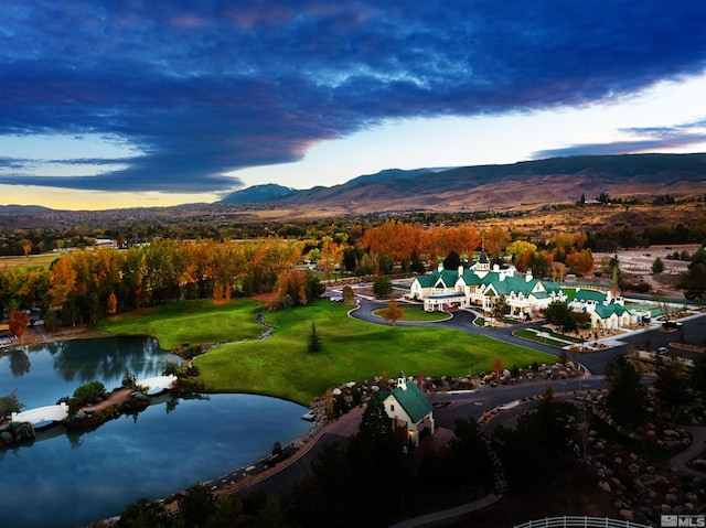 aerial view at dusk featuring a water and mountain view