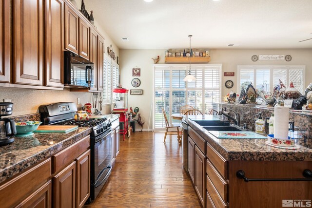 kitchen featuring range with gas cooktop, dark wood-style floors, brown cabinets, black microwave, and a sink