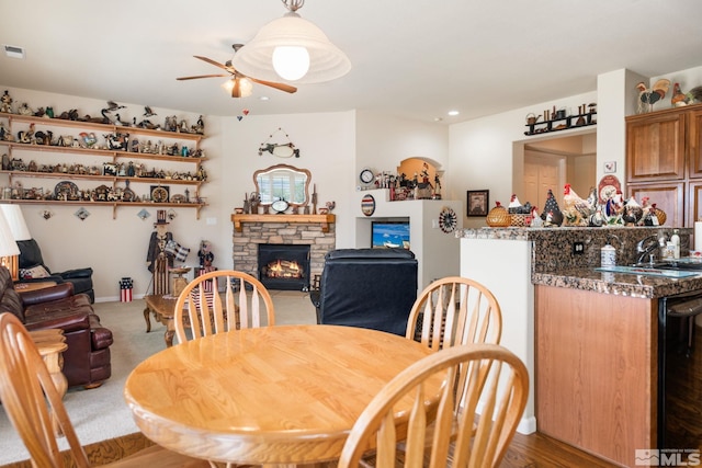 dining room featuring visible vents, ceiling fan, a stone fireplace, carpet floors, and indoor wet bar