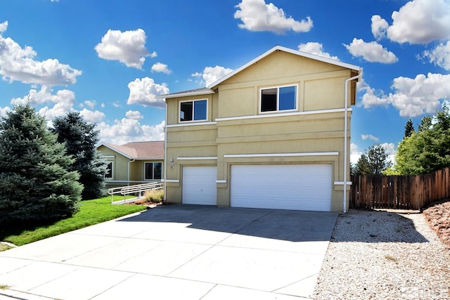 traditional-style house featuring a garage, concrete driveway, fence, and stucco siding