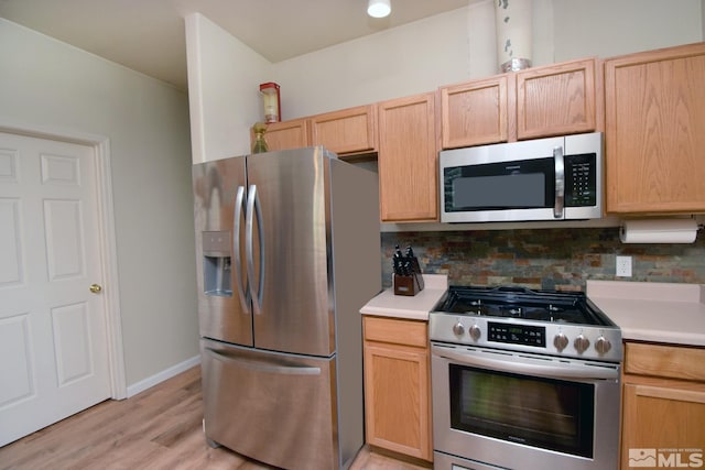 kitchen featuring stainless steel appliances, light countertops, light wood-style floors, and decorative backsplash