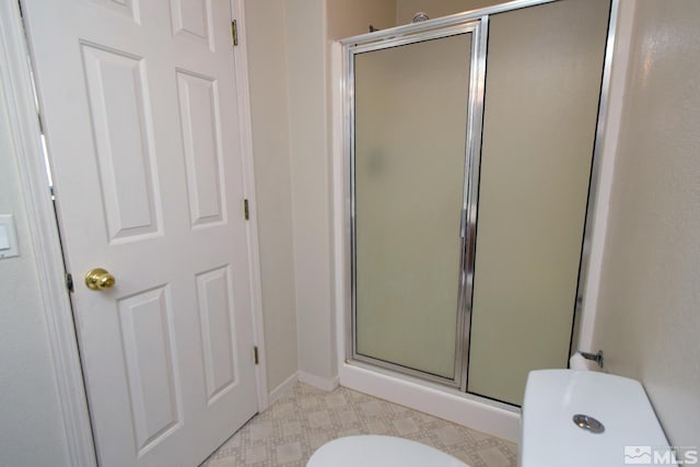 full bath with baseboards, a shower stall, toilet, and tile patterned floors