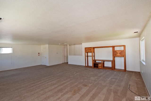 carpeted empty room with a textured ceiling and visible vents