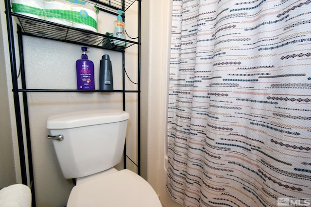 full bathroom featuring a shower with shower curtain and toilet