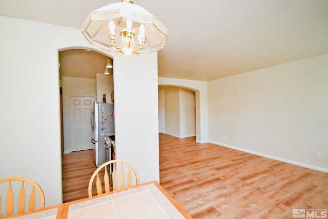 dining space with wood-type flooring and an inviting chandelier