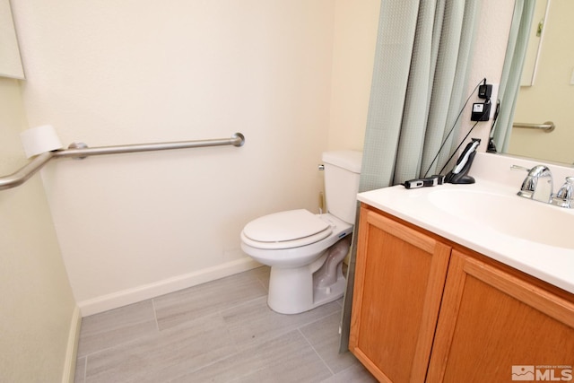 half bath with baseboards, vanity, and toilet