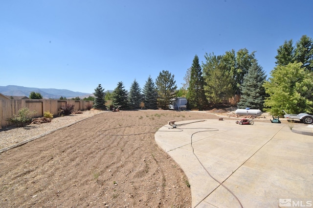 view of yard featuring a patio, fence, and a mountain view