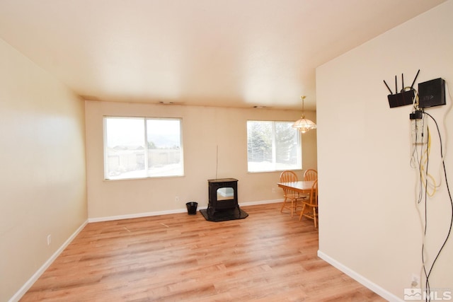 interior space with light wood-style flooring, a wood stove, and baseboards