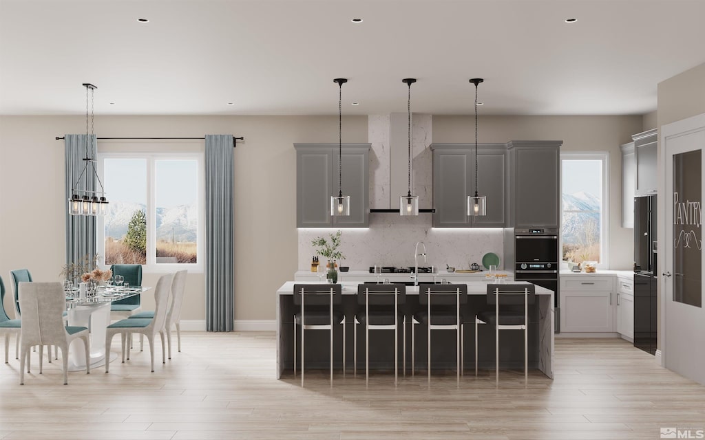 kitchen featuring a wealth of natural light, light hardwood / wood-style flooring, gray cabinetry, and a kitchen breakfast bar