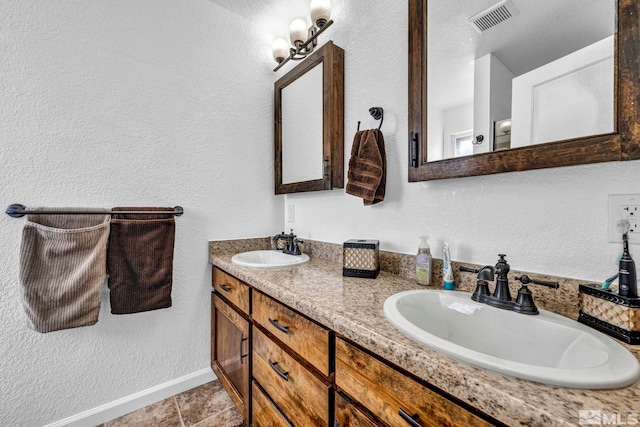 full bath featuring double vanity, a sink, visible vents, and baseboards