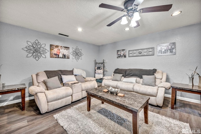 living room featuring a textured ceiling, baseboards, wood finished floors, and a textured wall