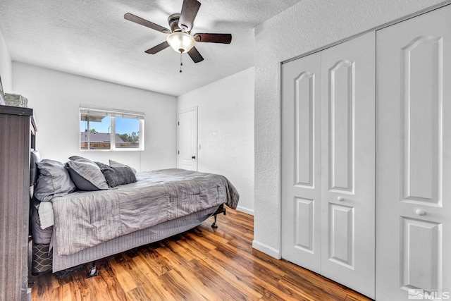 bedroom featuring a textured wall, ceiling fan, wood finished floors, a textured ceiling, and a closet