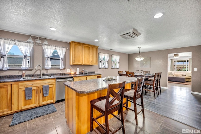 kitchen with a kitchen bar, a healthy amount of sunlight, dishwasher, and a sink