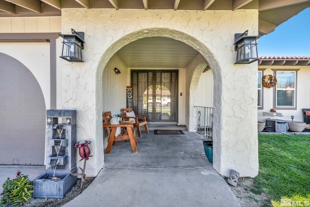 view of exterior entry with covered porch and stucco siding