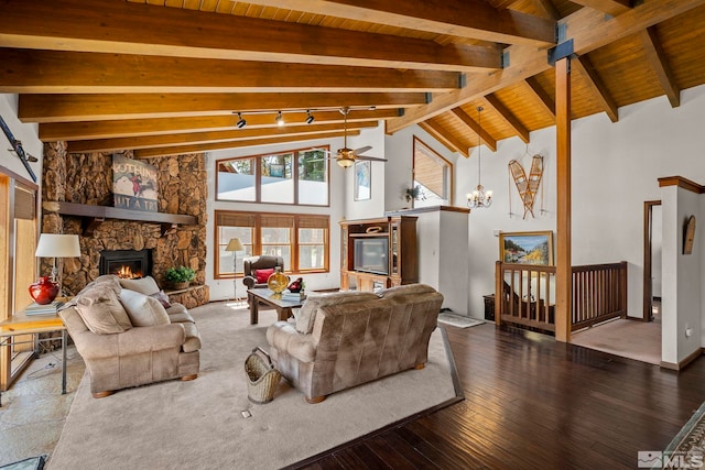 living room featuring beamed ceiling, ceiling fan, wood-type flooring, a stone fireplace, and high vaulted ceiling