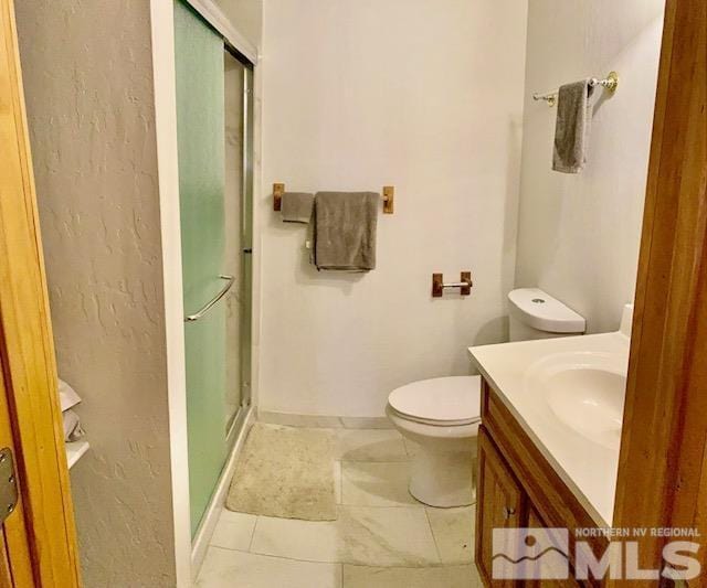 bathroom featuring tile patterned flooring, toilet, vanity, baseboards, and a shower stall