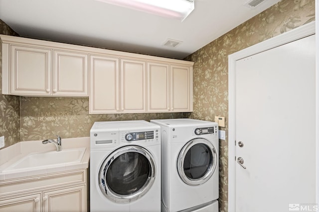 washroom with washing machine and clothes dryer, cabinets, and sink