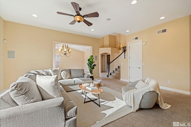 carpeted living room featuring ceiling fan with notable chandelier