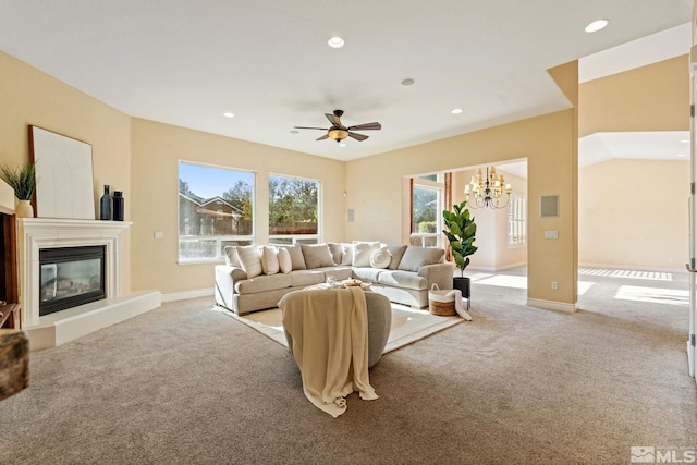 carpeted living room with ceiling fan with notable chandelier