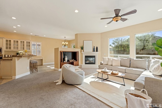 carpeted living room featuring ceiling fan with notable chandelier