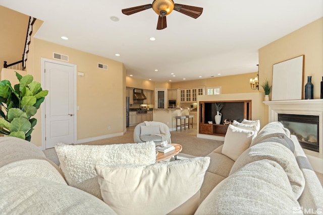 living room featuring ceiling fan with notable chandelier and light carpet