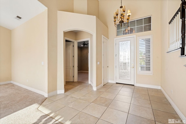 entrance foyer with ceiling fan with notable chandelier and light carpet