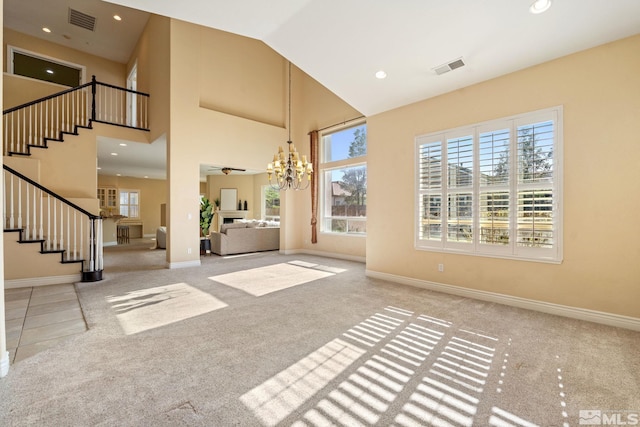 unfurnished living room featuring light colored carpet, high vaulted ceiling, and a chandelier