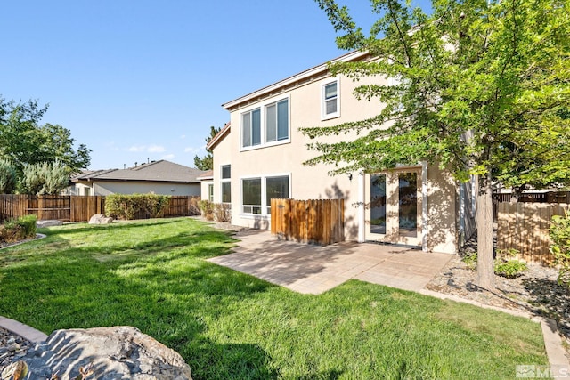 rear view of house with a lawn and a patio