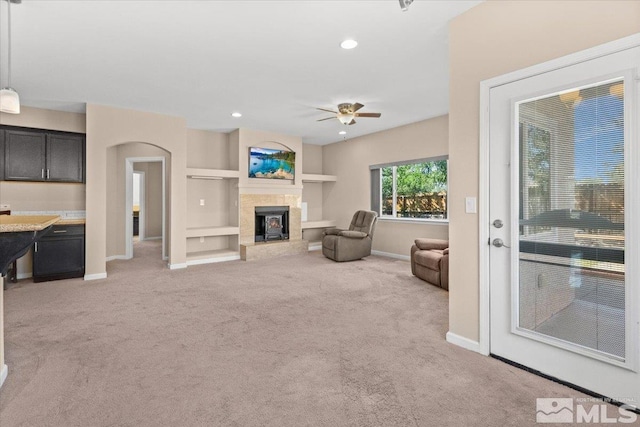 living room featuring built in features, a fireplace, recessed lighting, light carpet, and baseboards