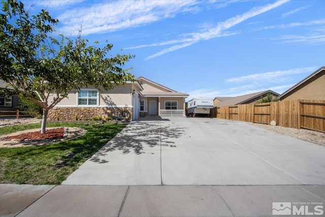 view of front facade with stone siding, concrete driveway, fence, and stucco siding