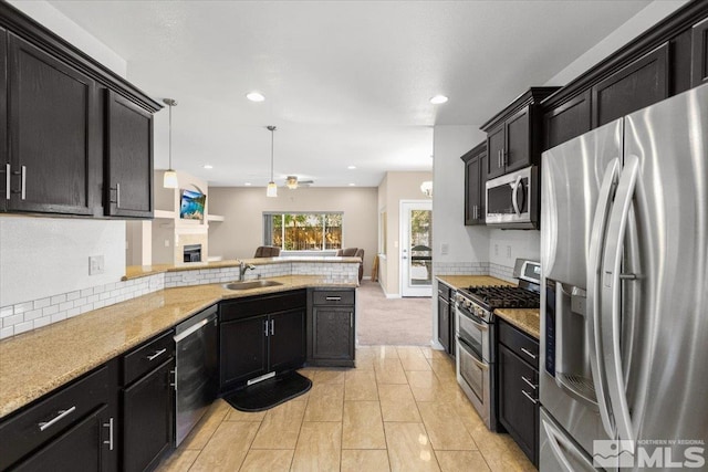 kitchen with stainless steel appliances, dark cabinets, a sink, and a peninsula