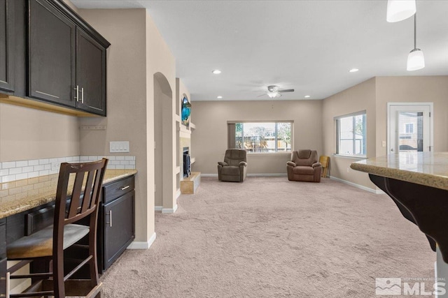 kitchen featuring light colored carpet, a fireplace with raised hearth, baseboards, and recessed lighting